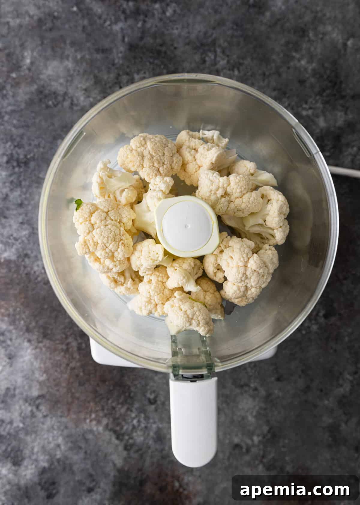 overhead: raw cauliflower in a food processor