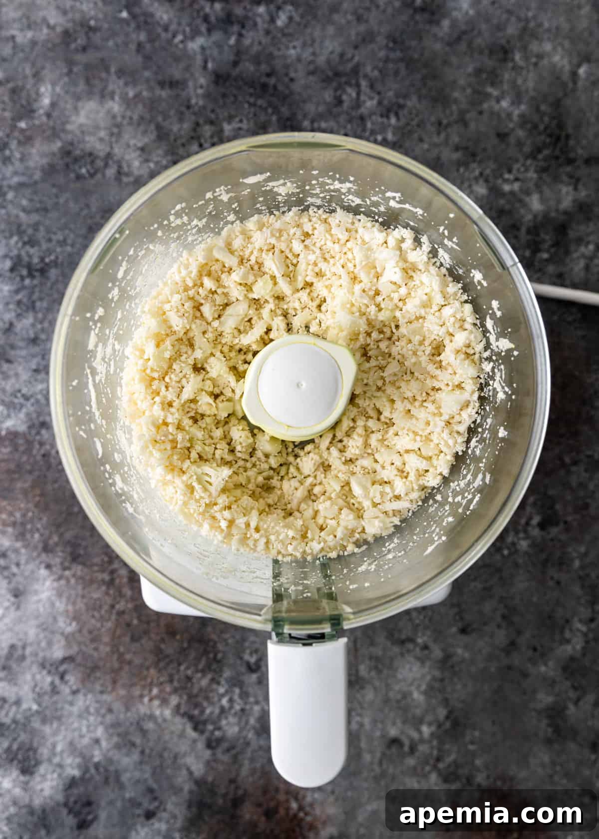 overhead: processed raw cauliflower in a food processort
