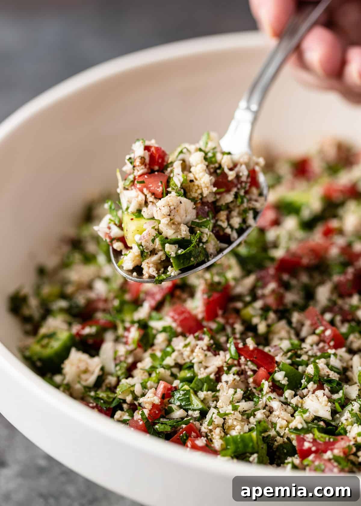 close up of cauliflower tabbouleh in a spoon over a bowl