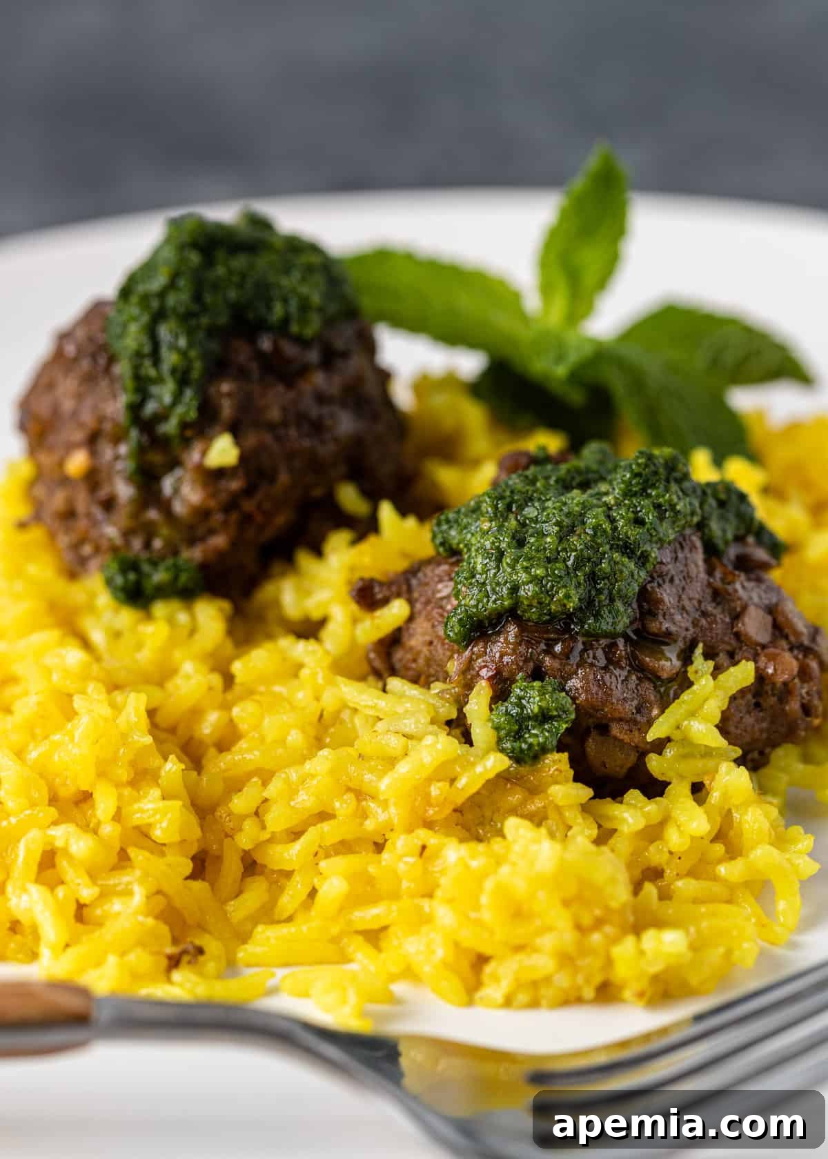 Mediterranean Lamb Lentil Meatballs and Zesty Lemon Rice 11 Close-up of two beautifully presented lamb meatballs over lemon rice, drizzled with vibrant mint pesto, showcasing the rich colors and textures of the dish.