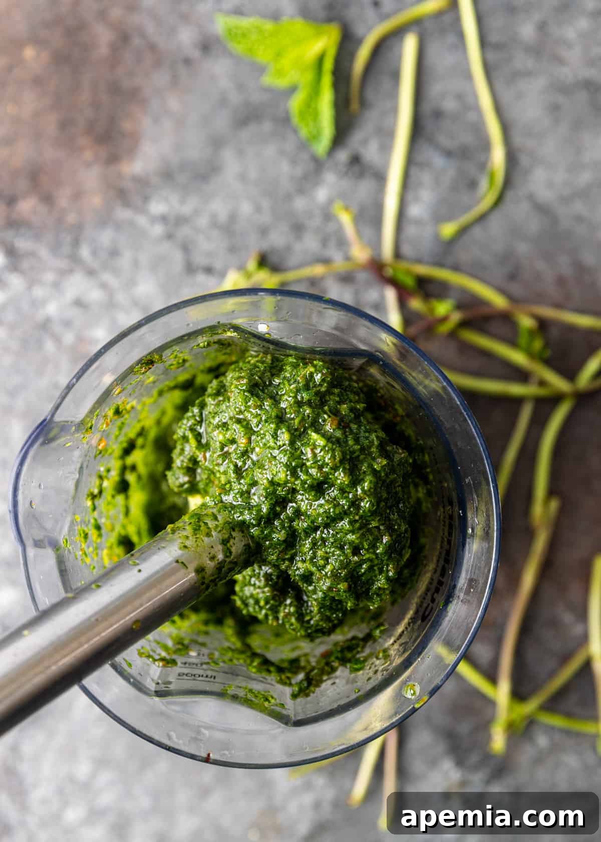 Mediterranean Lamb Lentil Meatballs and Zesty Lemon Rice 6 Overhead view of fresh mint, parsley, garlic, golden raisins, and olive oil being processed in a food processor to create the pesto.
