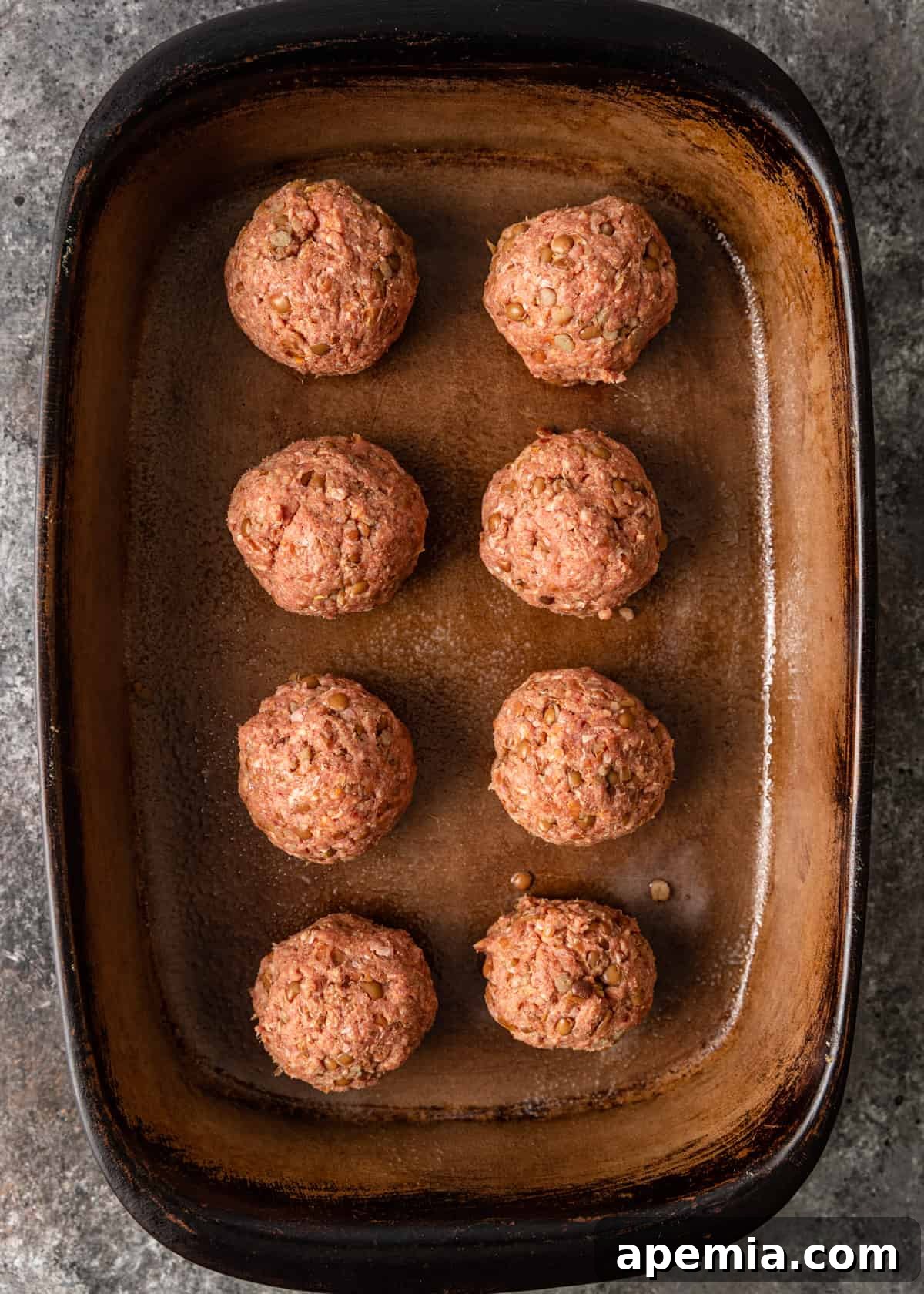 Mediterranean Lamb Lentil Meatballs and Zesty Lemon Rice 7 Overhead view of shaped lamb meatballs arranged in a baking dish, ready for roasting.