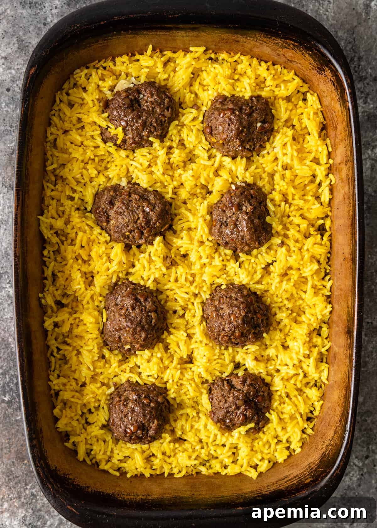 Mediterranean Lamb Lentil Meatballs and Zesty Lemon Rice 9 Overhead view of the lamb meatballs nestled in a bed of lemon jasmine rice, covered with foil and ready for the oven.