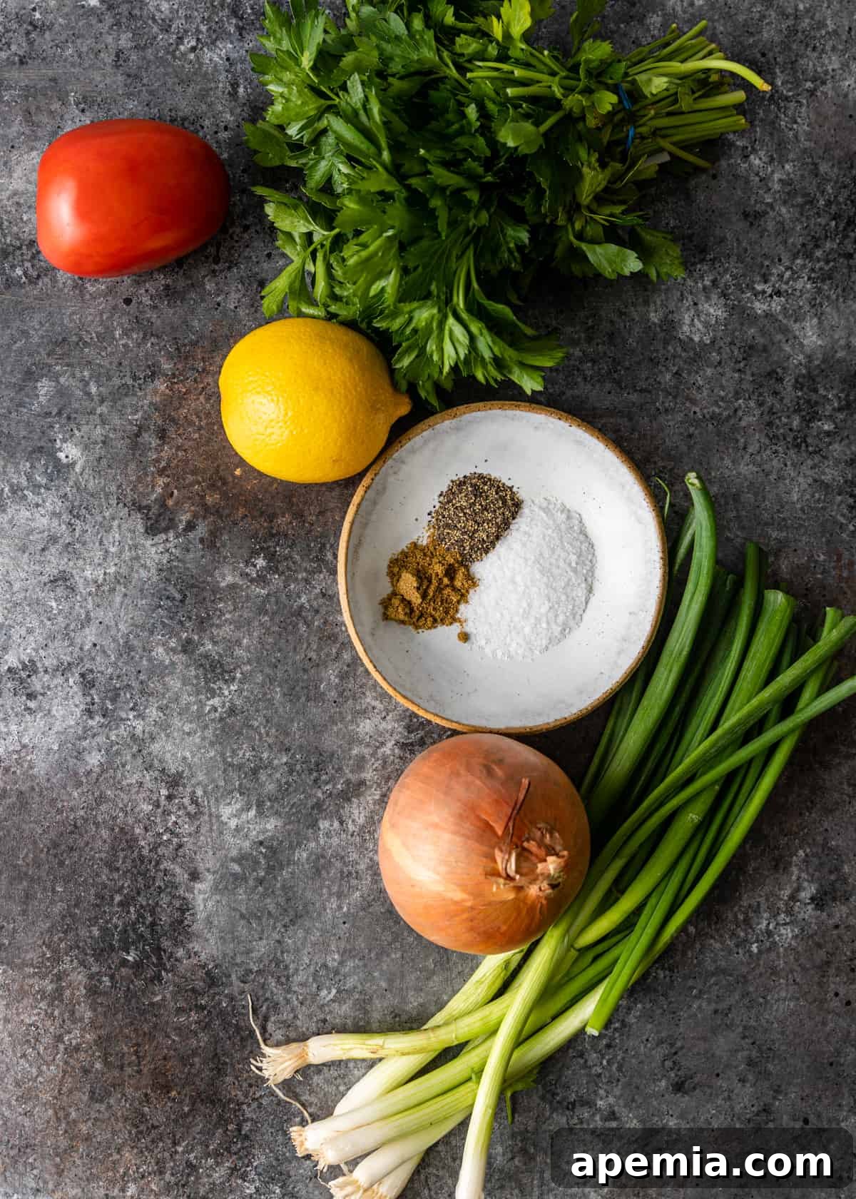 An array of fresh ingredients for Lebanese ful medames, including fava beans, chickpeas, herbs, tomatoes, and lemon.