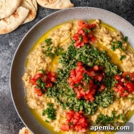 A beautifully presented serving of Lebanese Ful Medames in a bowl, garnished with fresh herbs.