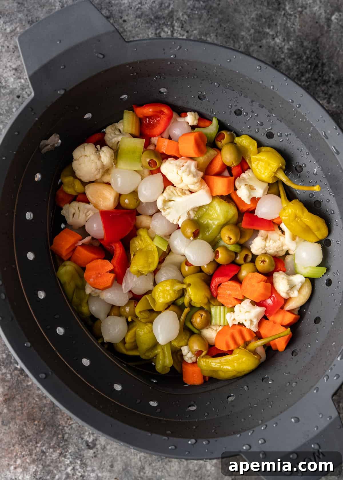 Overhead shot of rinsed vegetables neatly arranged in a colander after their salting process, ready for the next step in giardiniera preparation.