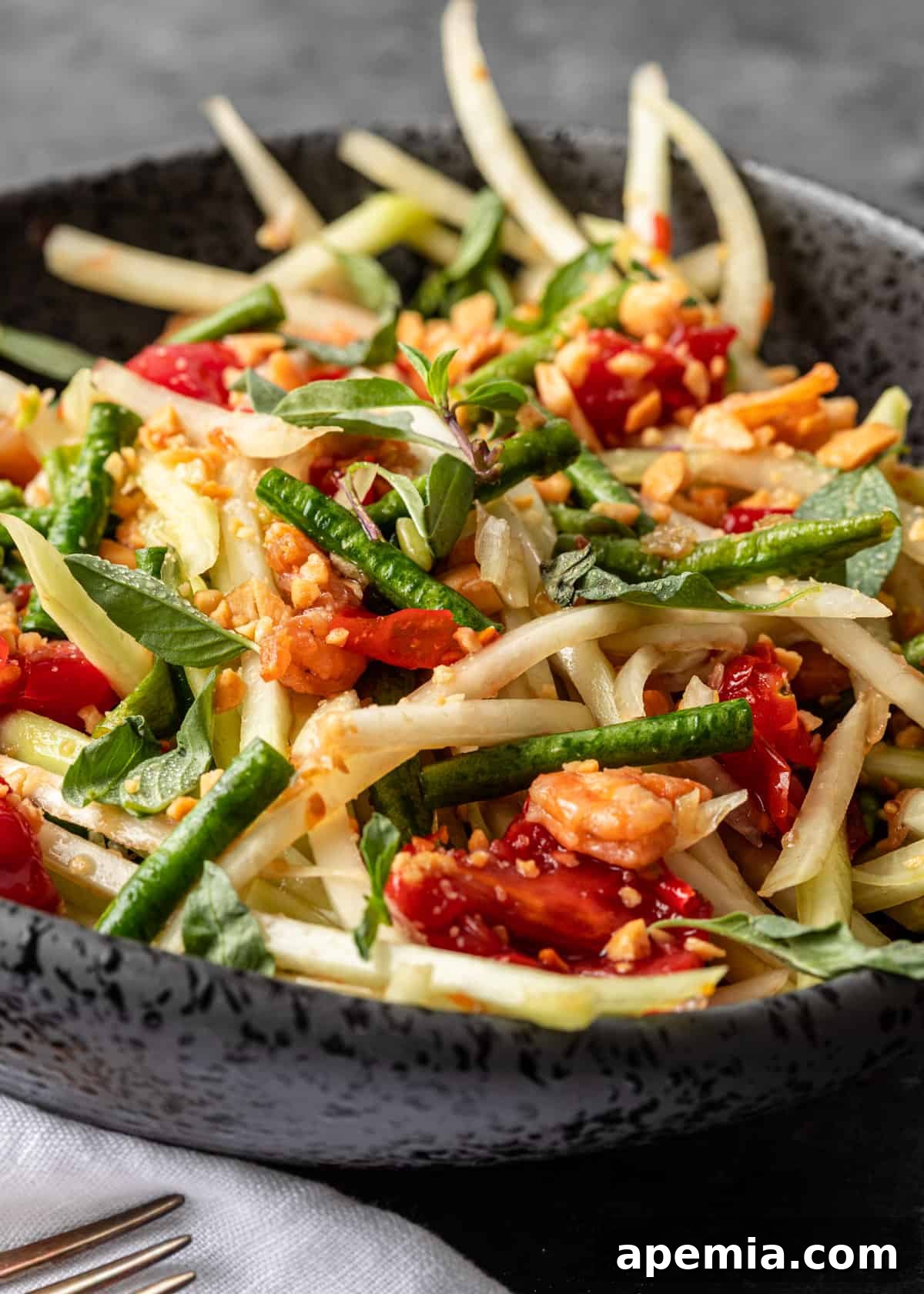 closeup: green papaya salad full of veggies, peanuts, and fruit