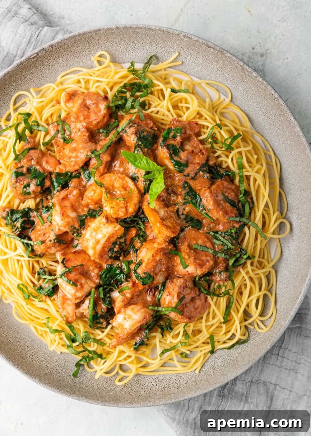 Overhead view of a heaping plate of Tuscan shrimp over spaghetti, showcasing the vibrant colors and generous portion.