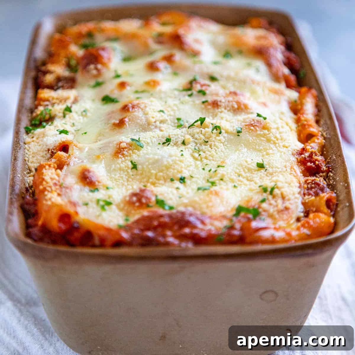 Close-up side view of baked ziti recipe after baking, showing melted cheese and golden edges