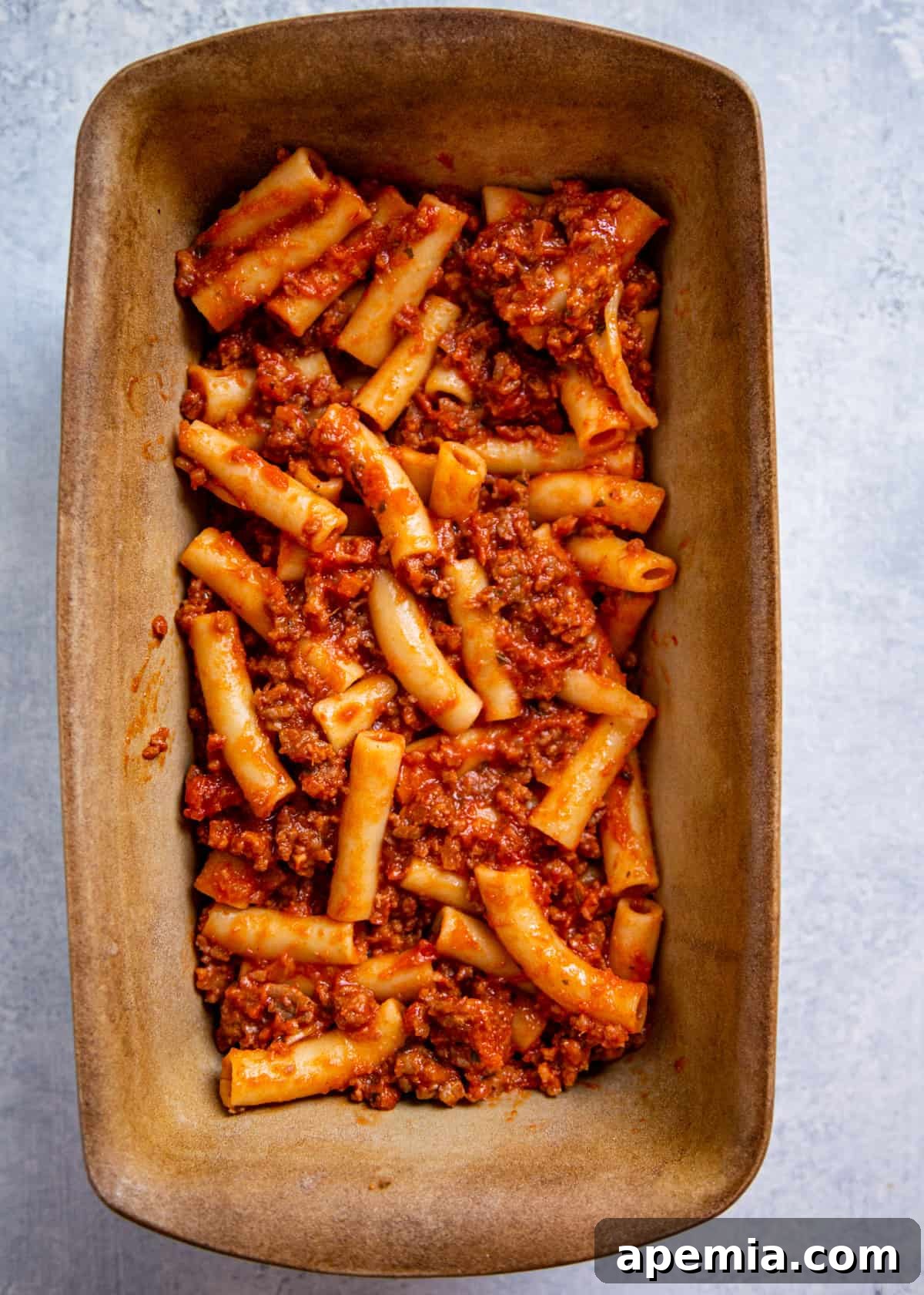 Overhead shot of ziti pasta and sauce in a baking dish, before adding cheese