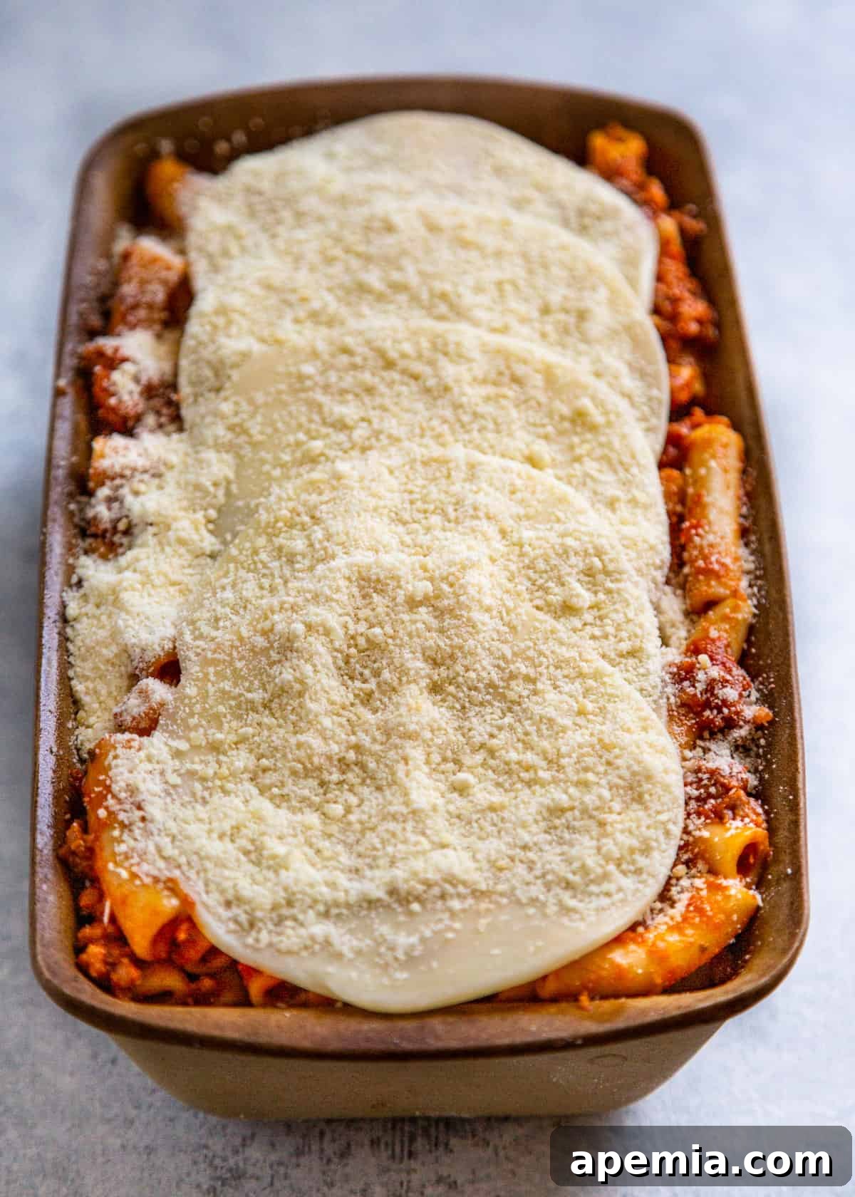 Overhead view of prepared baked ziti recipe topped with cheese, ready for baking
