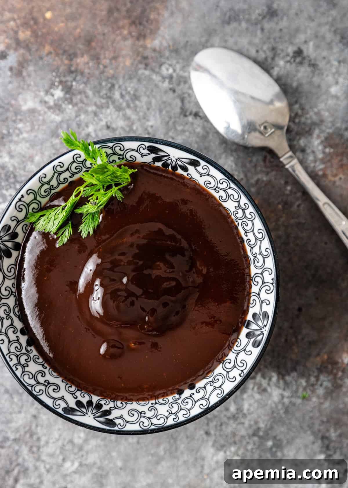 overhead: a black and white bowl of tonkatsu sauce with herbs