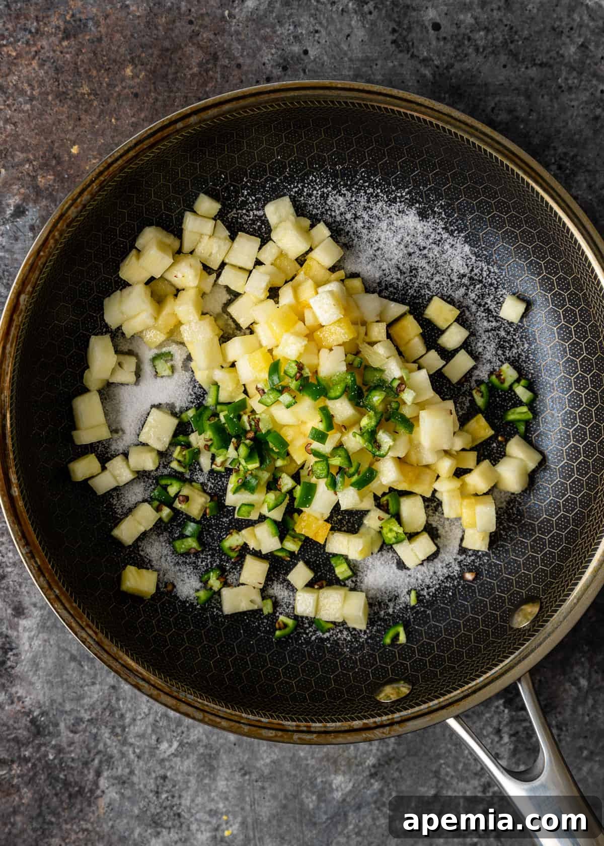 overhead: sautéed pineapple and serrano chiles in a skillet