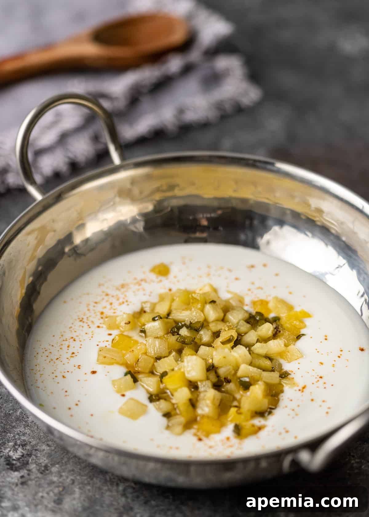 pineapple raita in a metal dish with sautéed pineapples on top