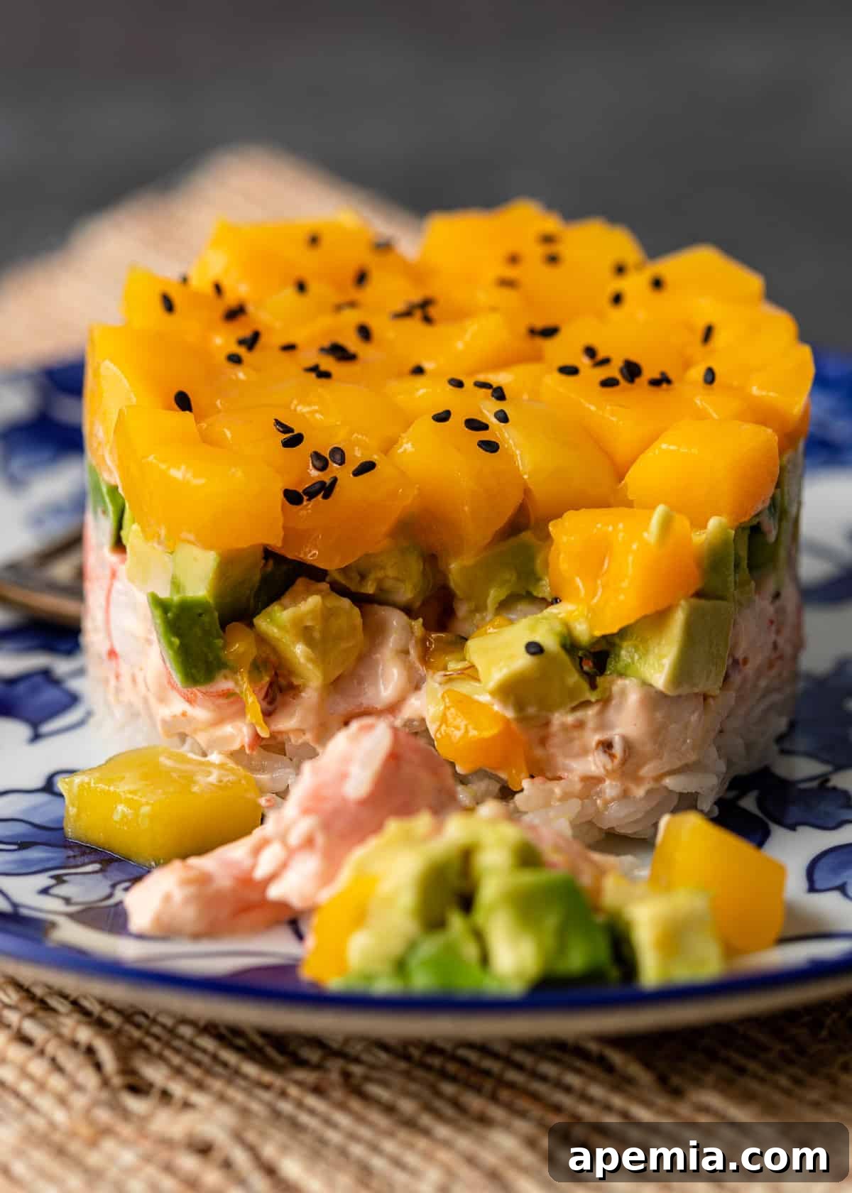 Closeup view of a shrimp sushi stack with a fork taking a bite, revealing the intricate layers