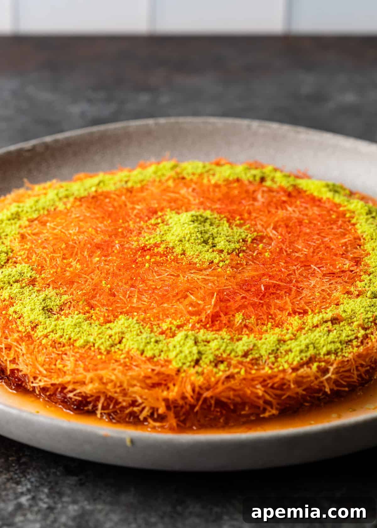 Close-up of a finished knafeh, generously topped with finely chopped pistachios.