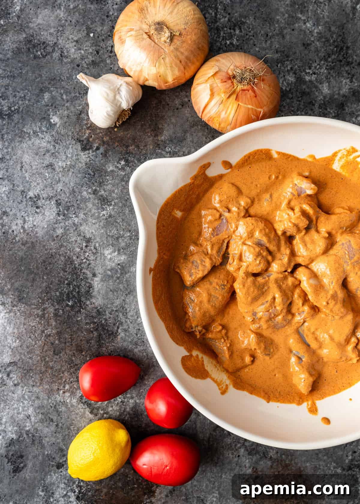 overhead: chicken thighs marinating in a large white bowl