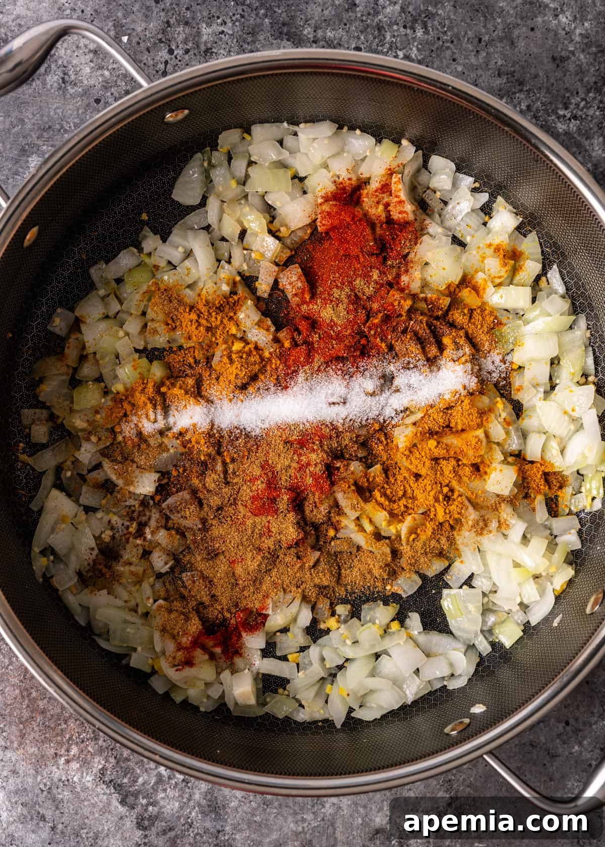 overhead process shot: adding spices to onion, garlic, and ginger in a pot