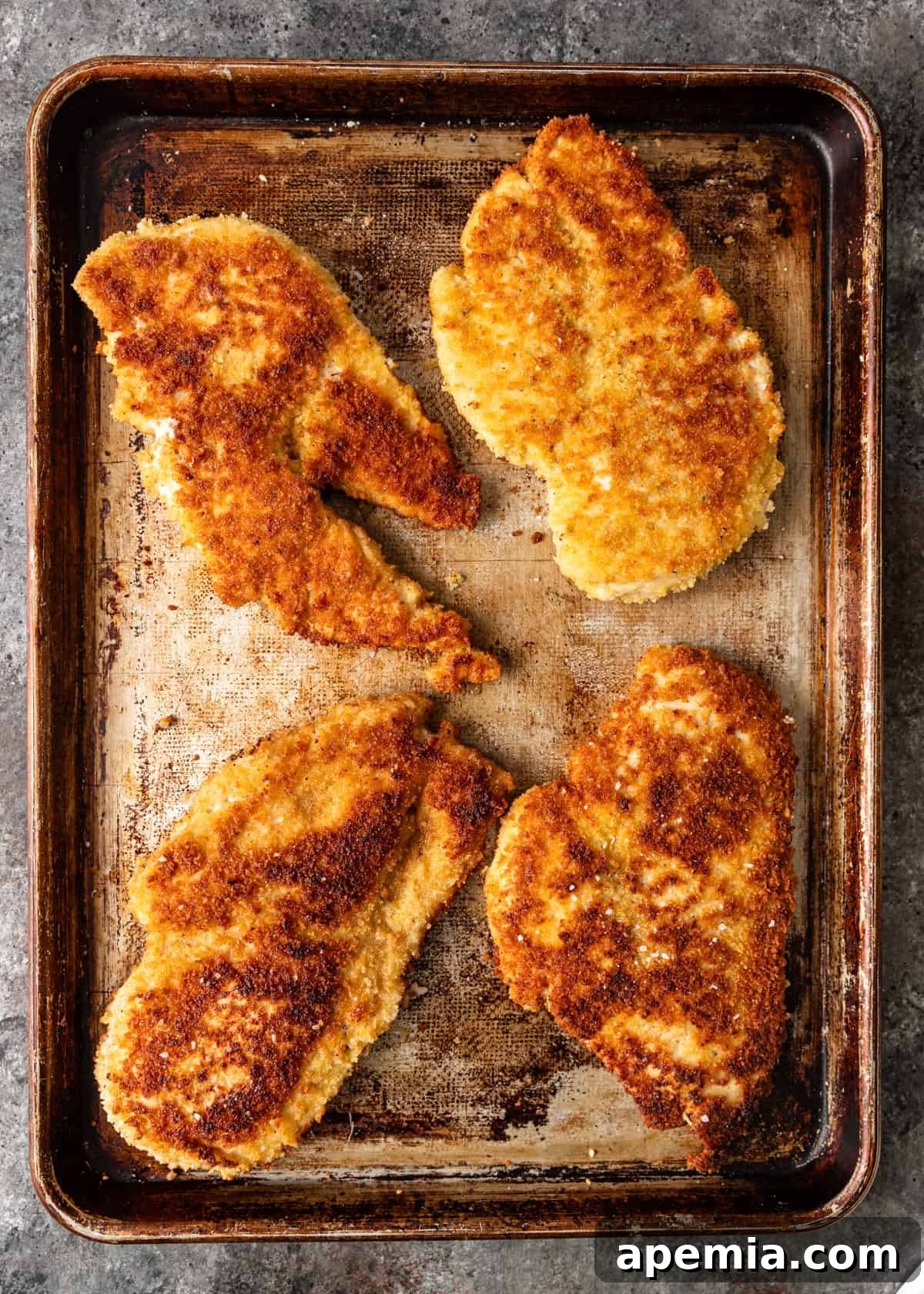 overhead: cooked breaded chicken breasts on a baking sheet