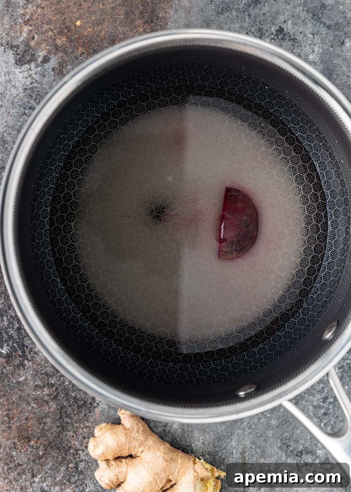 A small saucepan on a stovetop, with beet slices, rice vinegar, sugar, and water simmering to create the pickling brine.