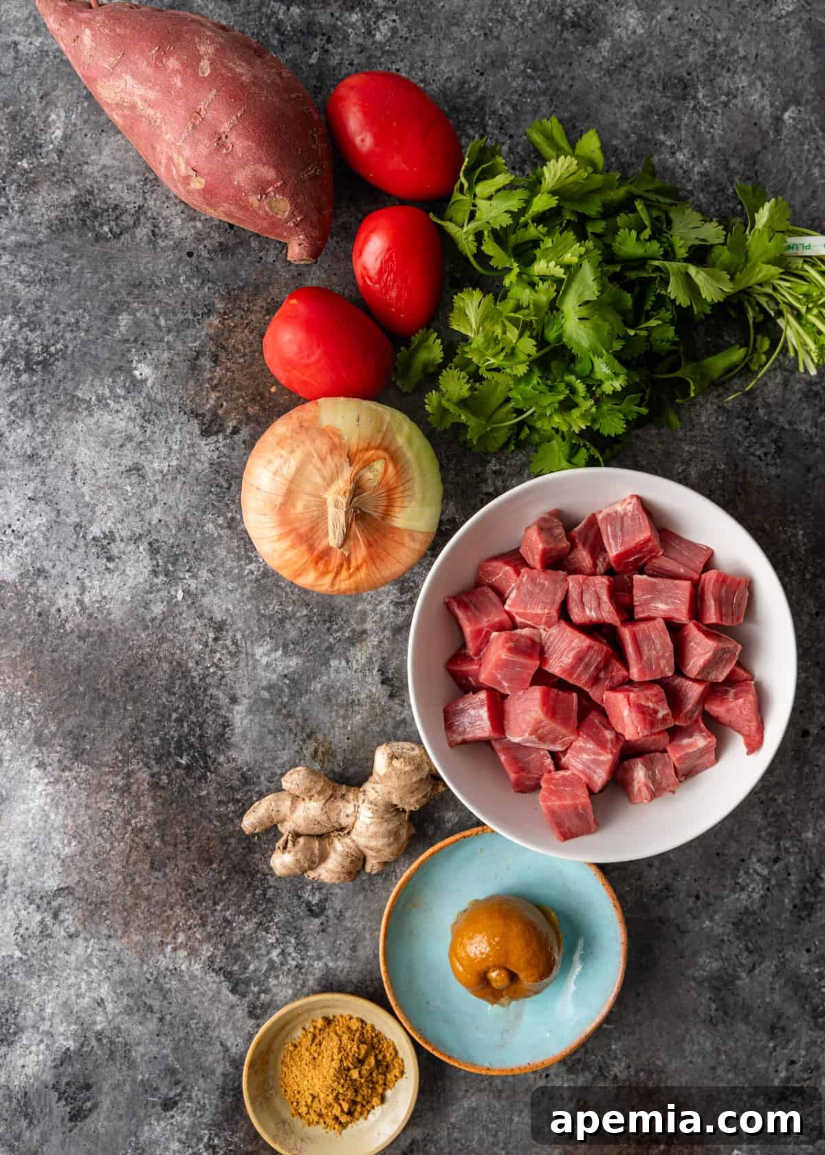 Spiced Beef and Sweet Potato Tagine 4 Overhead flat lay of all fresh ingredients required for beef tagine: beef cubes, sweet potatoes, peas, tomatoes, onion, ginger, garlic, preserved lemons, and spices.