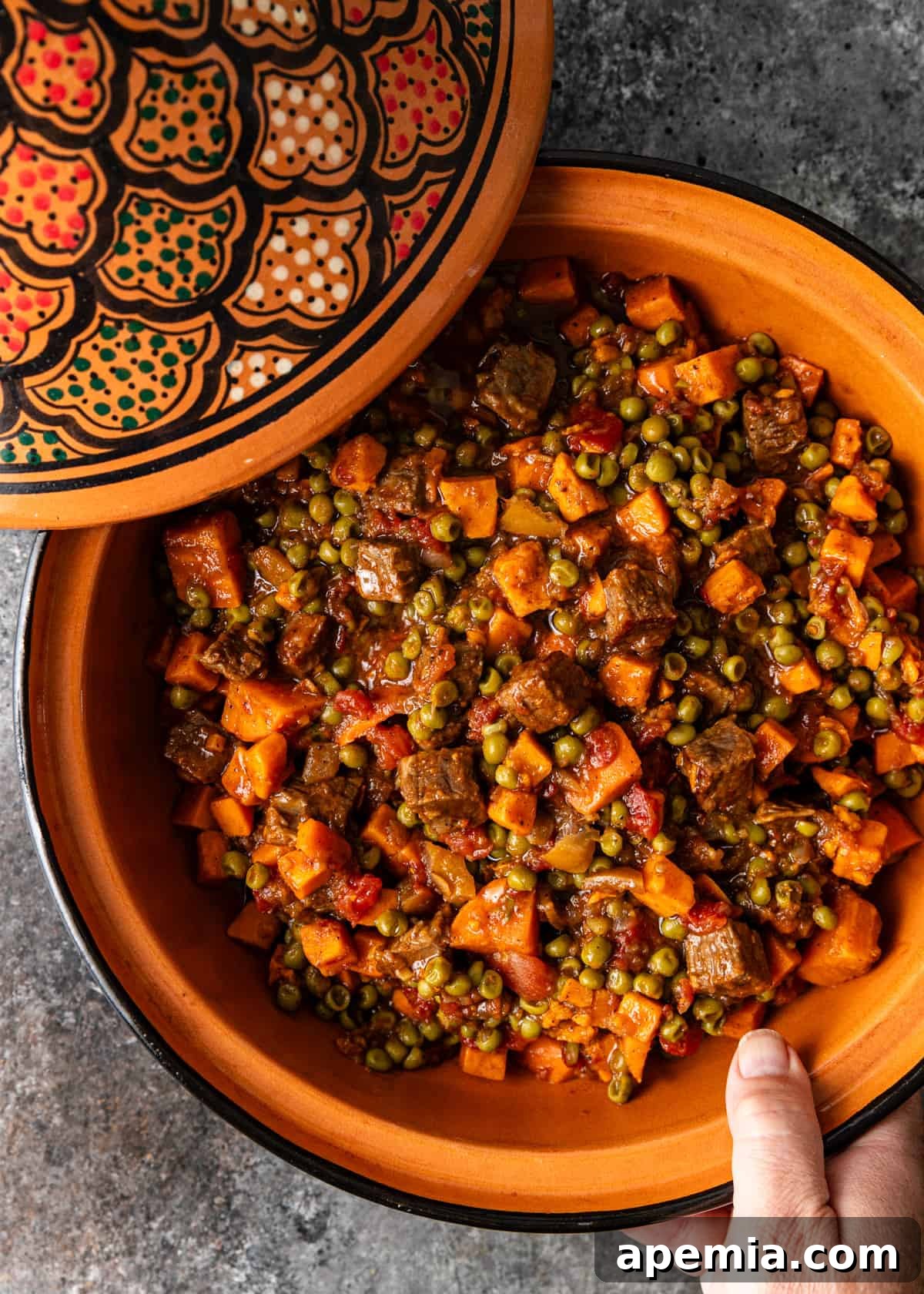 Spiced Beef and Sweet Potato Tagine 8 Overhead closeup of a traditional ceramic tagine pot filled with the cooked beef tagine, its lid resting beside it on a wooden surface.