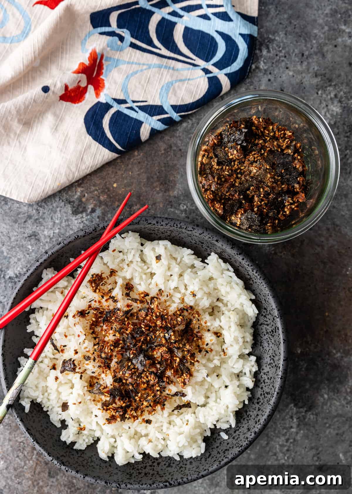 overhead: furikake over white rice in a bowl with extra Japanese rice seasoning to the right