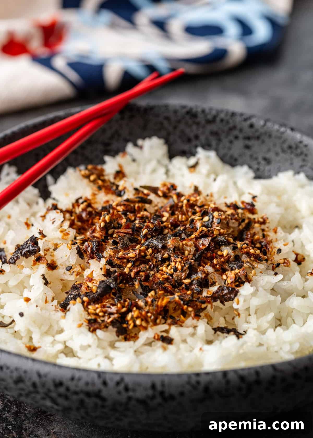 closeup: Japanese rice seasoning over white rice in a bowl with red chop sticks