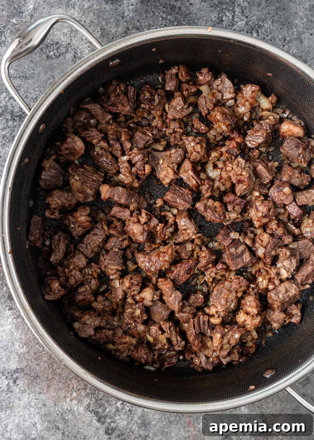 overhead process shot: seasoned beef cubes in deep skillet