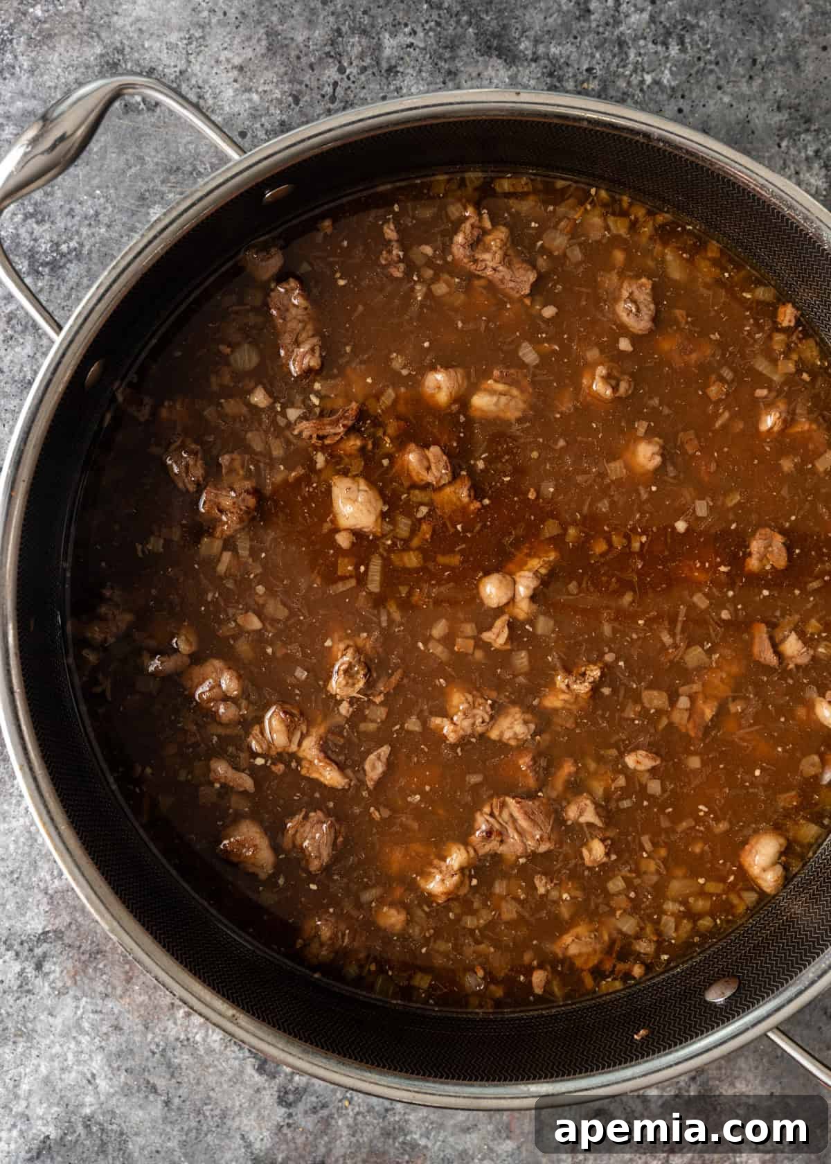 overhead process shot: water added to seasoned beef cubes in deep skillet