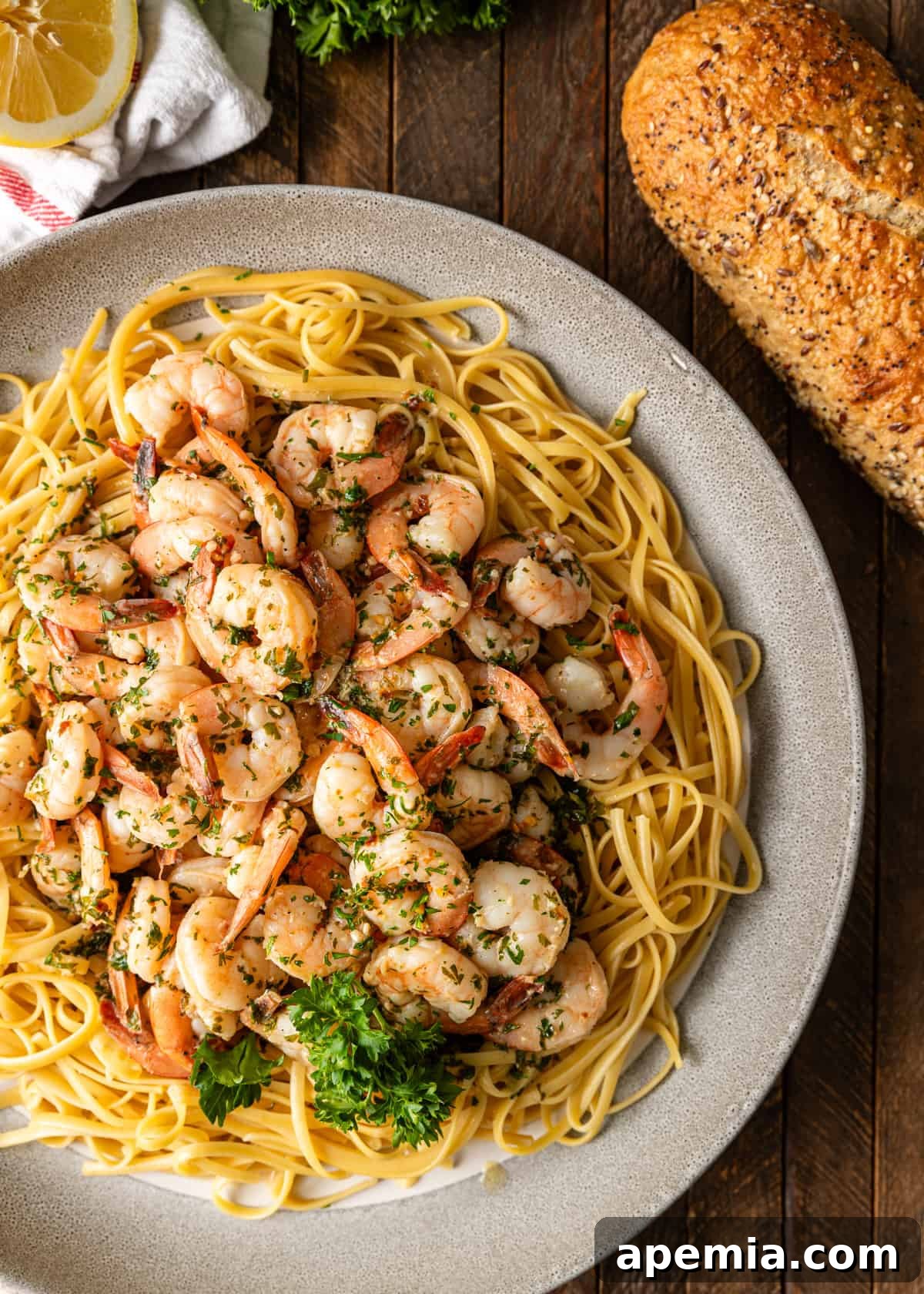 overhead: shrimp scampi pasta on a plate with bread on the side