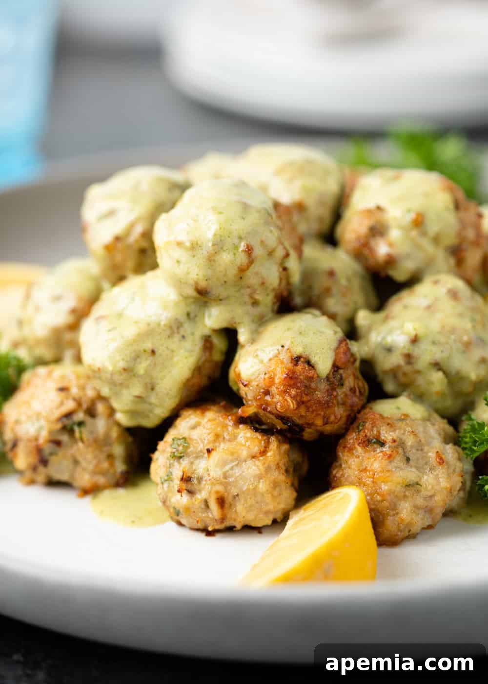 Close-up shot of chicken meatballs bathed in creamy Alfredo sauce, ready to be enjoyed.