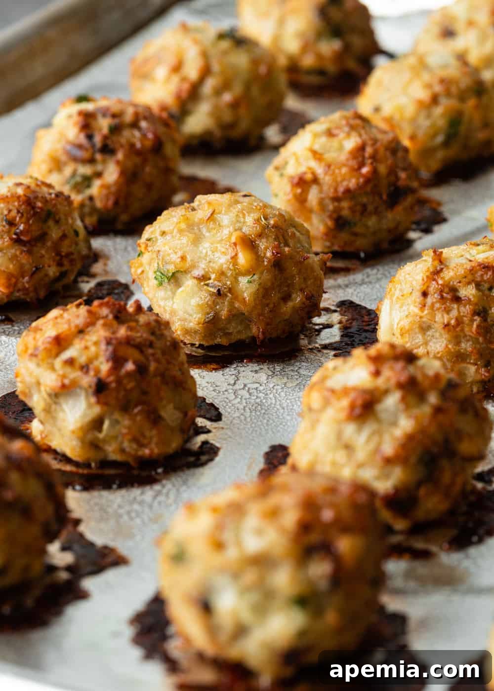 Close-up shot of perfectly formed chicken parm meatballs arranged on a baking dish before cooking.