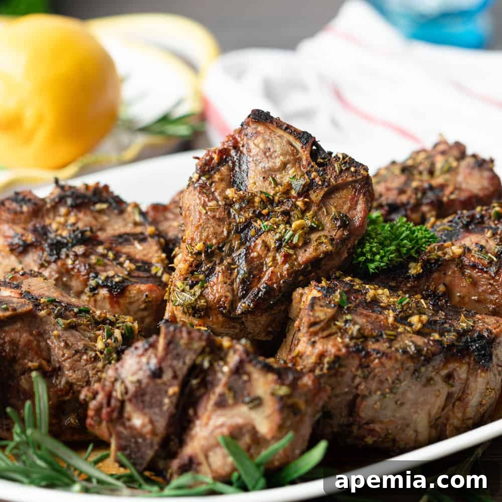 closeup: lamb loin chops on a serving platter, garnished with fresh rosemary and lemon slices
