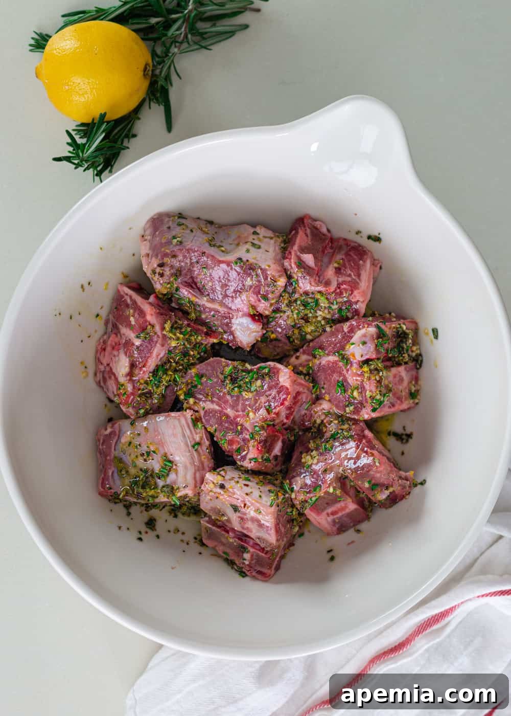 overhead: greek lamb chops in a bowl with marinade, showing the marinating process