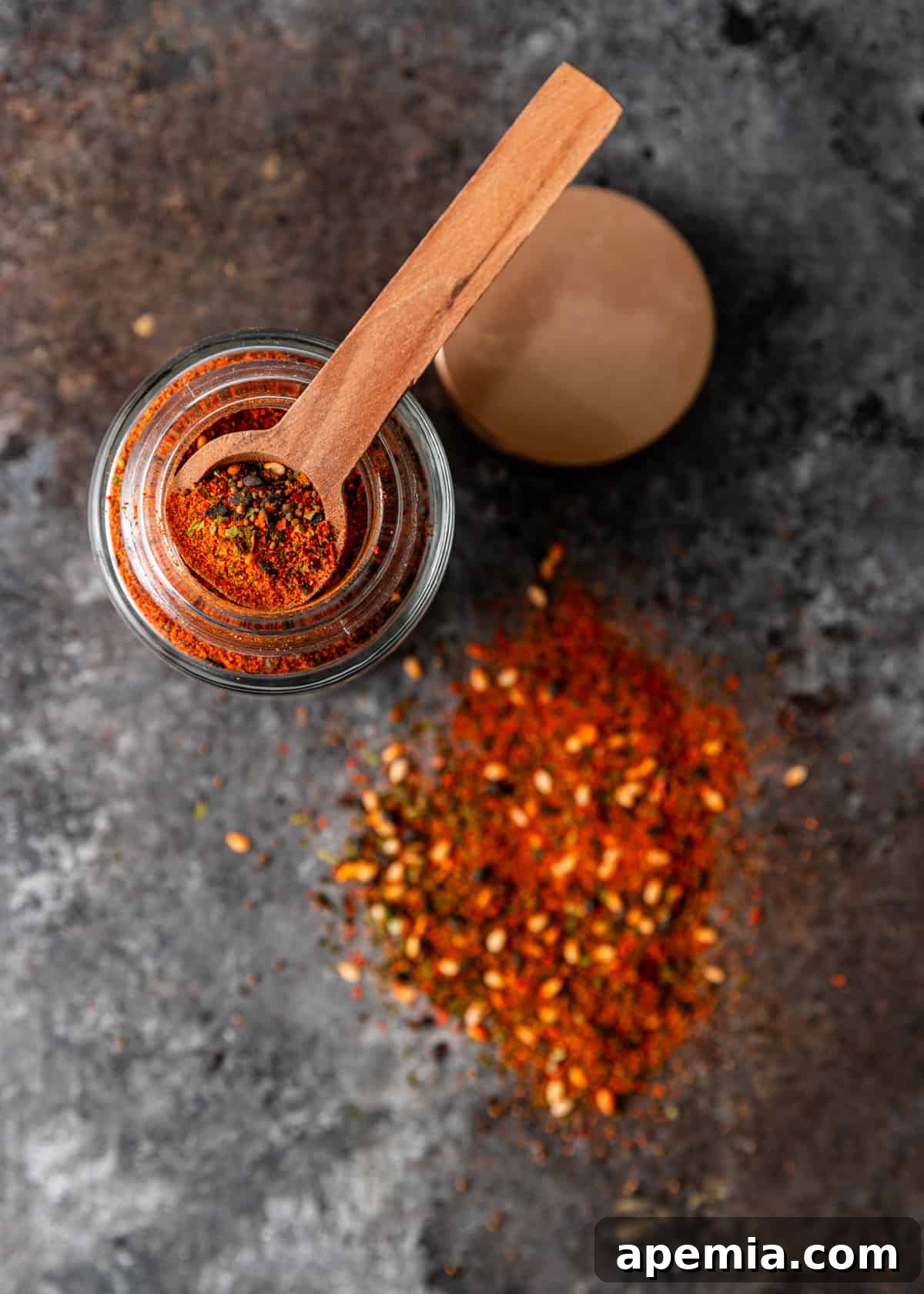 Overhead view of a beautifully labeled jar of homemade Shichimi Togarashi spice blend with a small wooden spoon, positioned elegantly on a countertop.