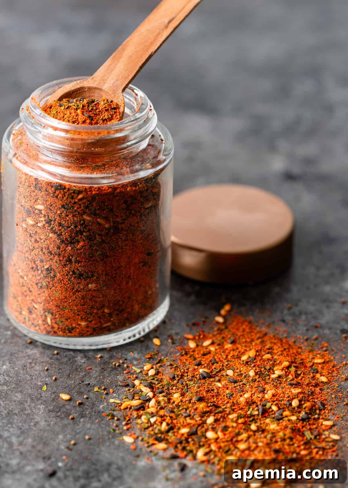 Side view of an elegant jar filled with homemade Shichimi Togarashi Japanese spice blend, with a portion of the spice scattered on the counter, emphasizing its handcrafted allure.