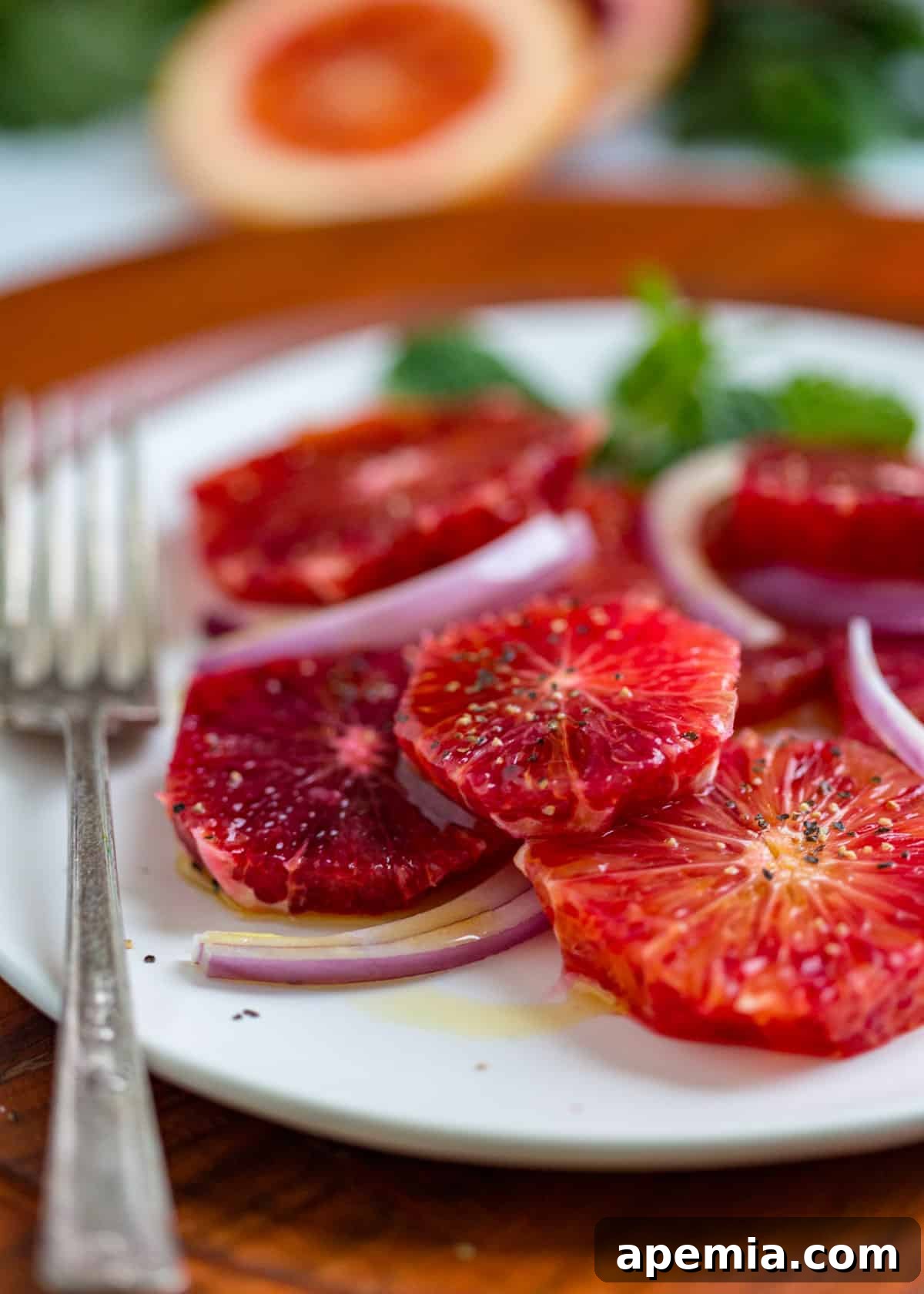 Close-up view of blood orange salad with a visible sprinkle of salt and freshly ground pepper on top.