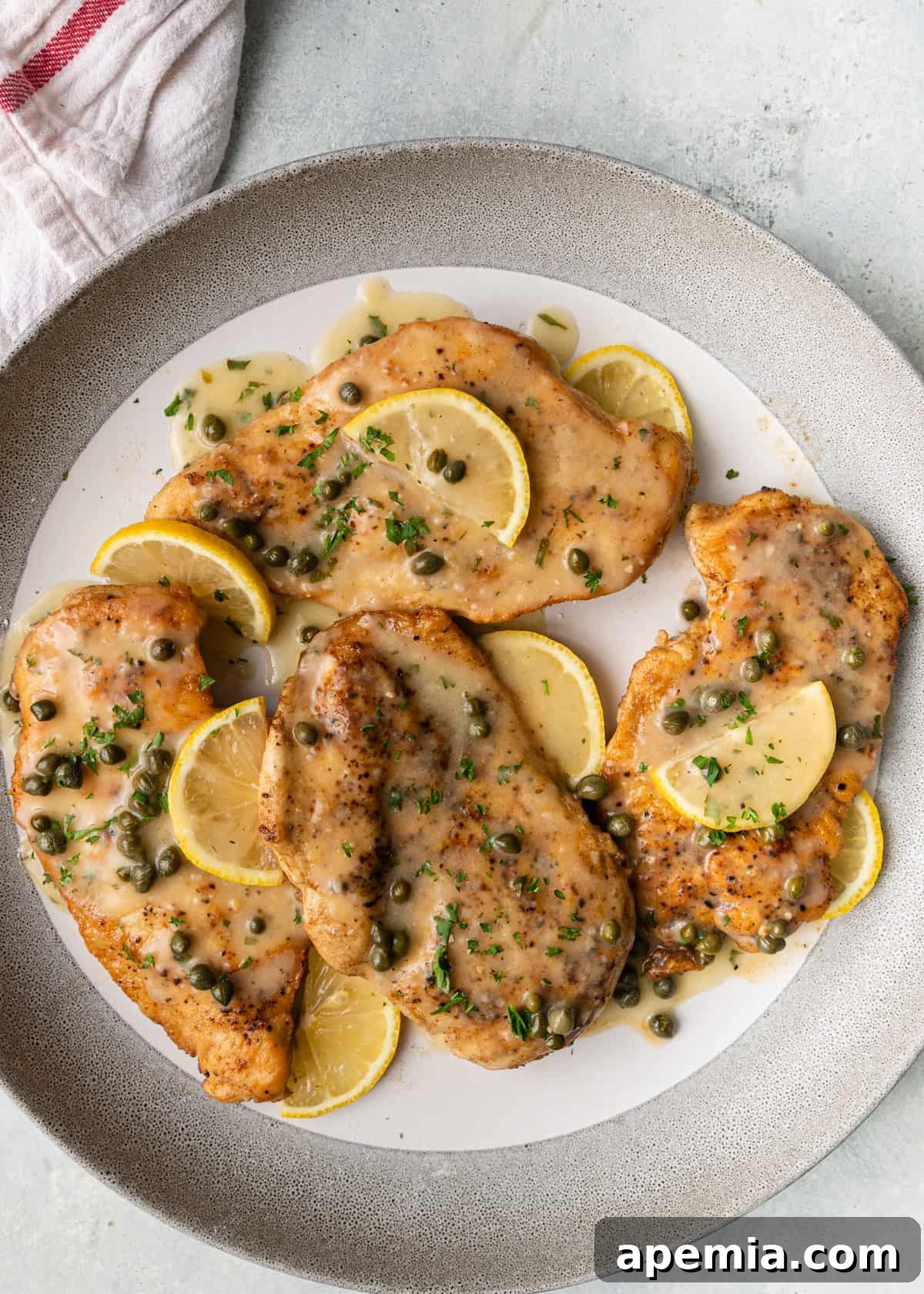 Zesty Lemon Caper Chicken 5 Overhead view of perfectly breaded and pan-fried chicken piccata cutlets artfully arranged on a plate, topped with the vibrant lemon and caper sauce.