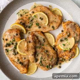 Final plated chicken piccata with sauce, lemon, and capers.
