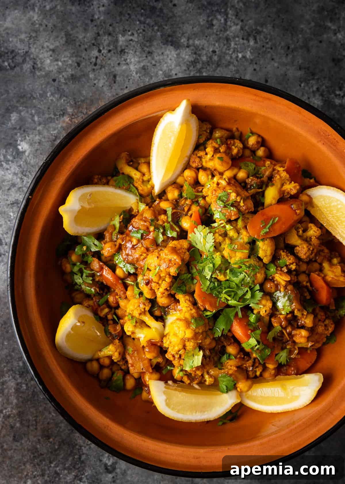 Moroccan Cauliflower and Carrot Tagine 3 Overhead shot of a Moroccan vegetable tagine in a ceramic bowl, beautifully garnished with fresh lemon wedges.