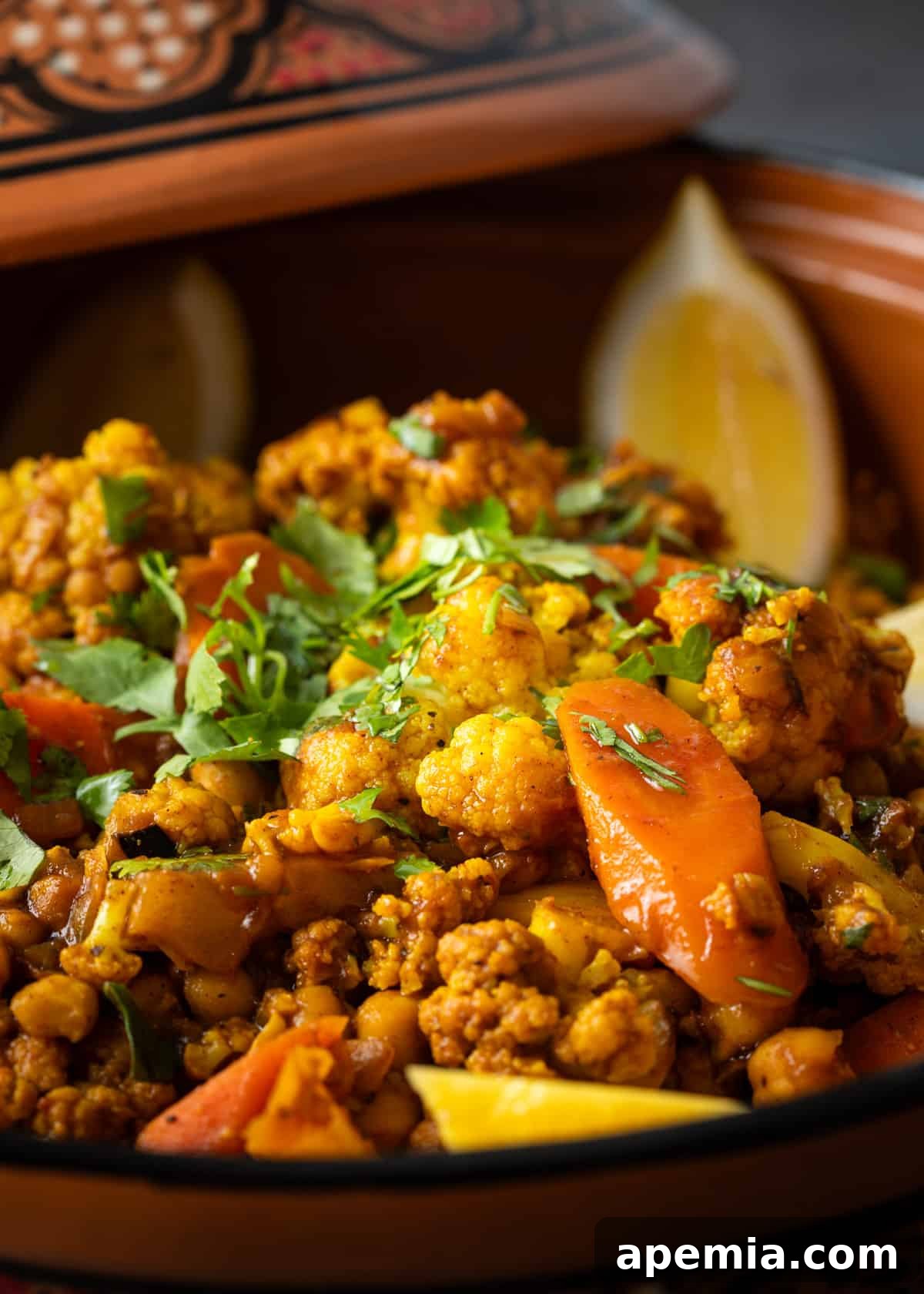 Moroccan Cauliflower and Carrot Tagine 7 Side view of the vegetable tagine in a ceramic bowl, garnished with fresh herbs on top, highlighting its hearty and inviting appearance.