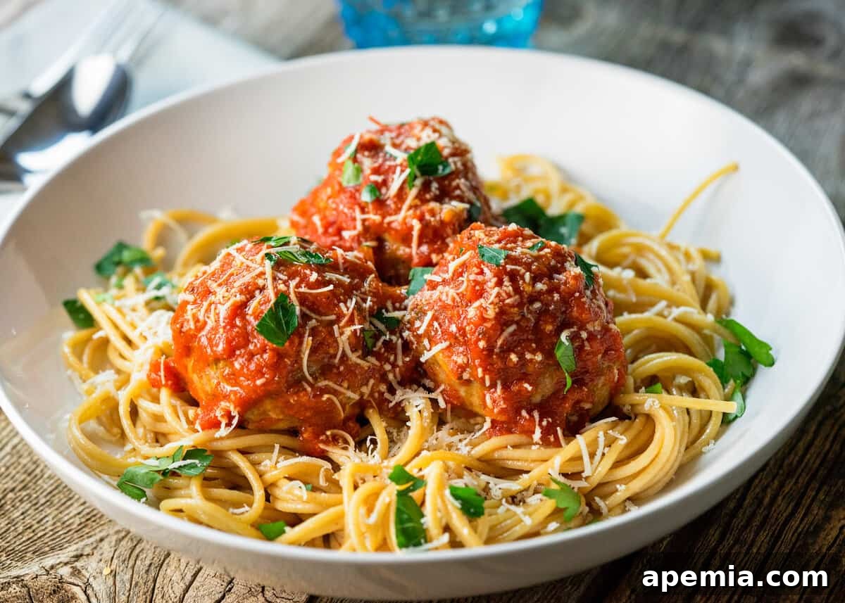 Polpette alla Romana (Roman style meatballs) with sauce served over spaghetti in an elegant white bowl.
