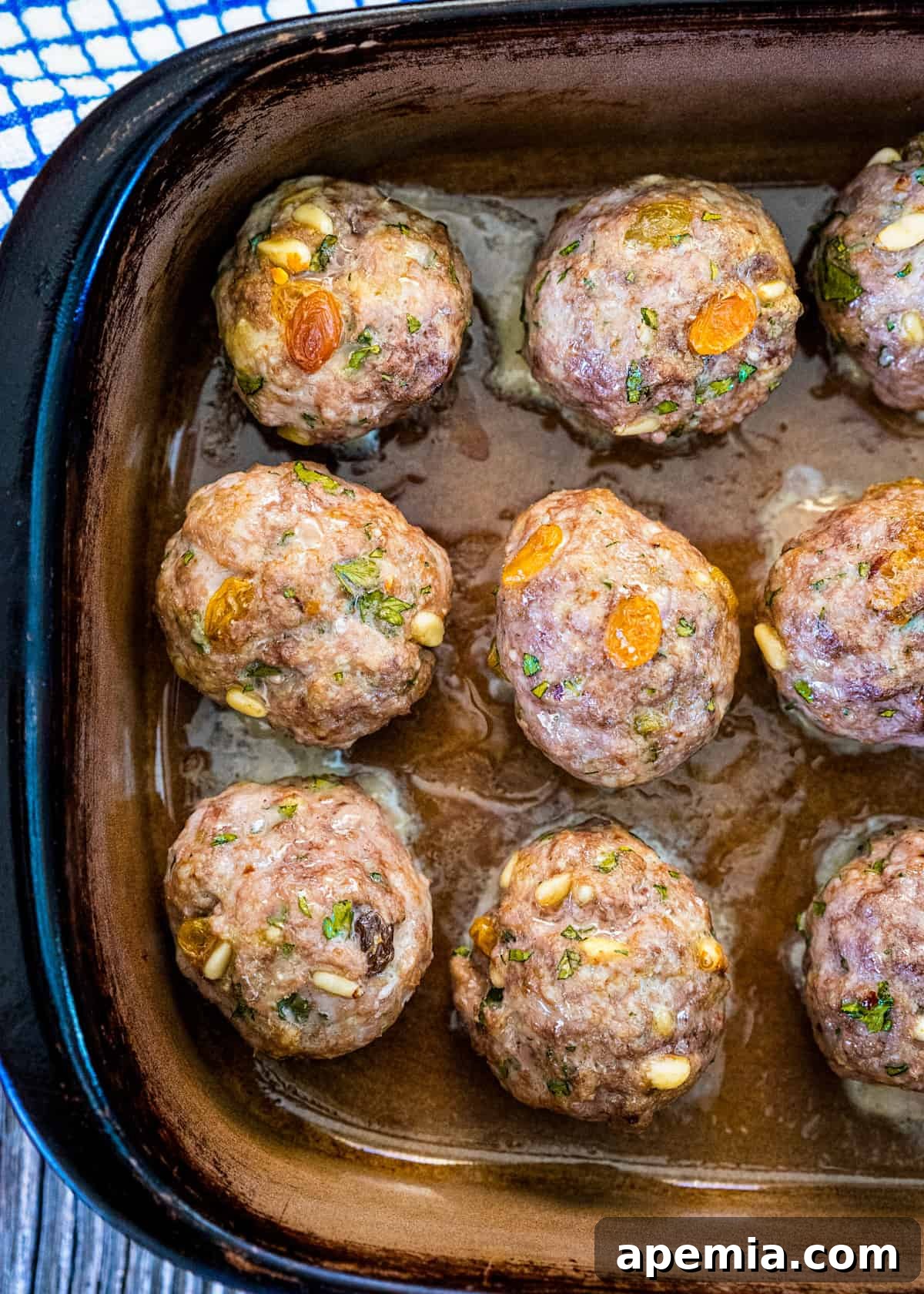 Overhead closeup: Baked Polpette alla Romana in a rustic baking dish, showcasing their rich texture and golden finish.