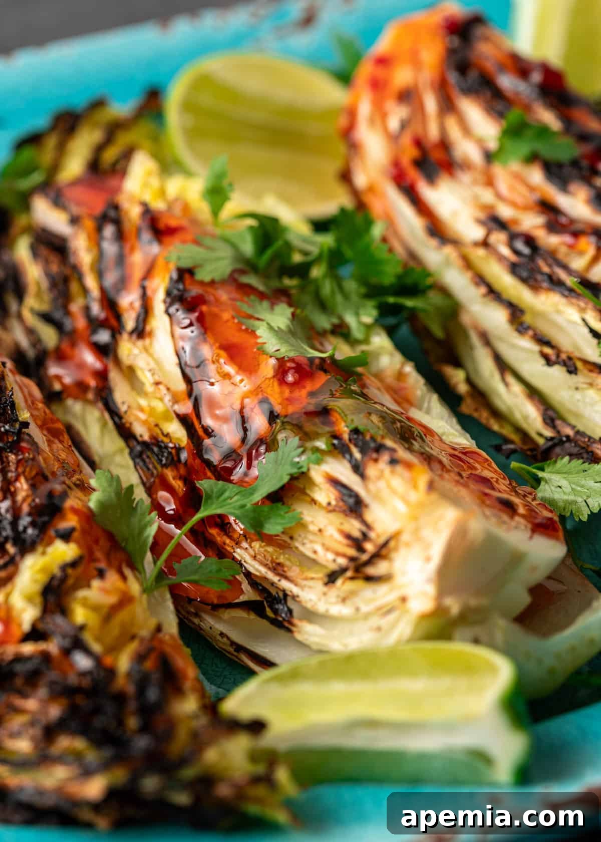 Sweet Chili Glazed Grilled Cabbage 3 Extreme close-up of a charred grilled cabbage wedge, glistening with sweet chili sauce, garnished with vibrant fresh cilantro and a slice of lime.