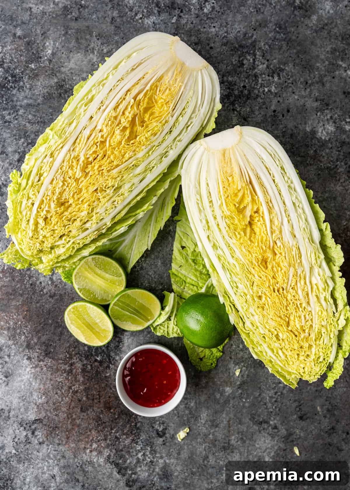 Sweet Chili Glazed Grilled Cabbage 4 Overhead view of all the fresh ingredients laid out on a wooden board, ready for this grilled cabbage recipe, including napa cabbage, limes, cilantro, and sweet chili sauce.