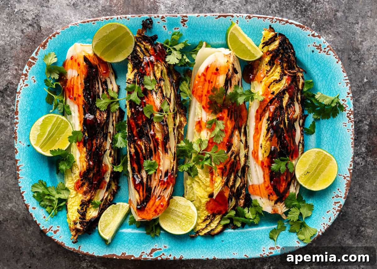 Sweet Chili Glazed Grilled Cabbage 6 Overhead view of grilled cabbage halves on a blue serving platter, artfully drizzled with sweet chili sauce, ready to be cut and served.