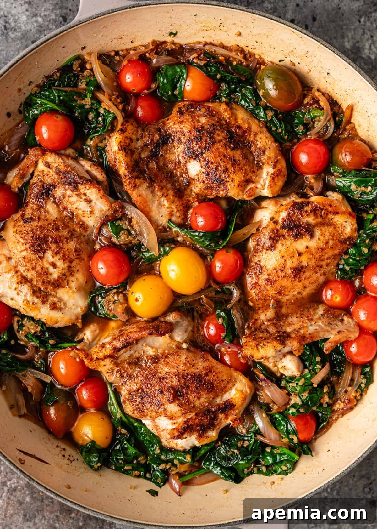 Chicken being added back into the skillet with the bulgur and vegetable mixture, nestled and pressed down before covering and baking.
