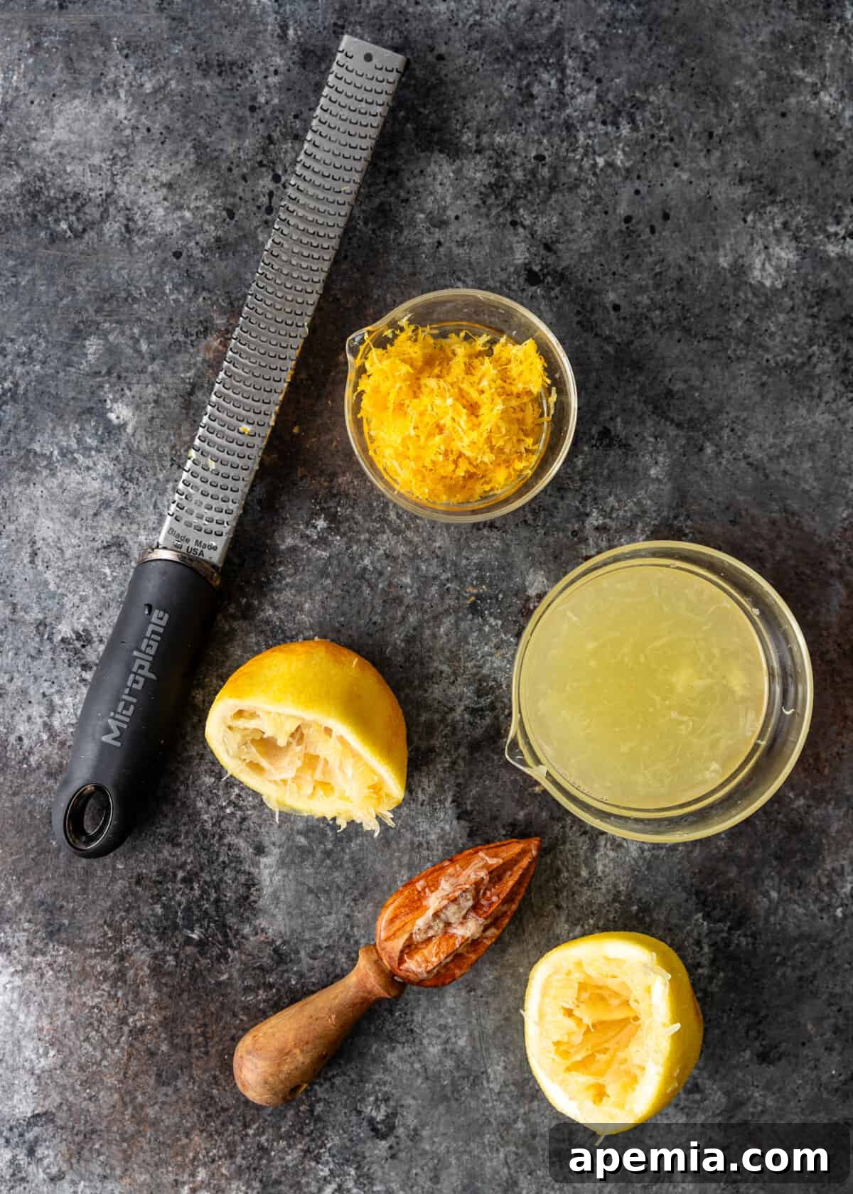 Zesty Creamy Lemon Posset 6 Overhead view of lemon zest on a zester, a juiced lemon half, a bowl of fresh lemon juice, and a bowl of lemon zest.