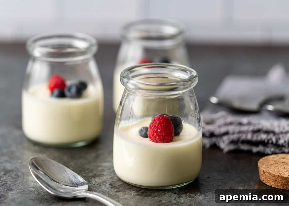 Zesty Creamy Lemon Posset 8 Three individual glass jars filled with finished lemon posset, topped with an assortment of fresh berries.